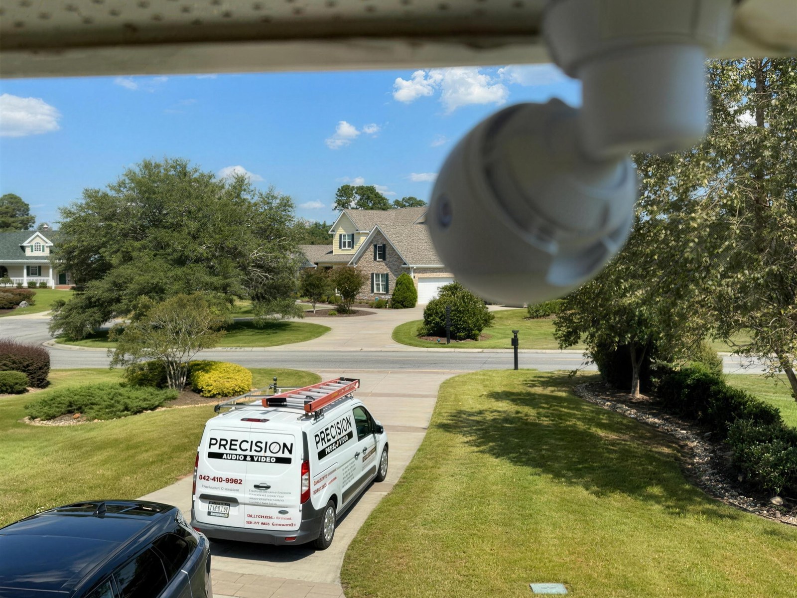 A Precision Audio & Video van in the driveway of a Grand Strand home, seen past a security camera mounted under the eaves